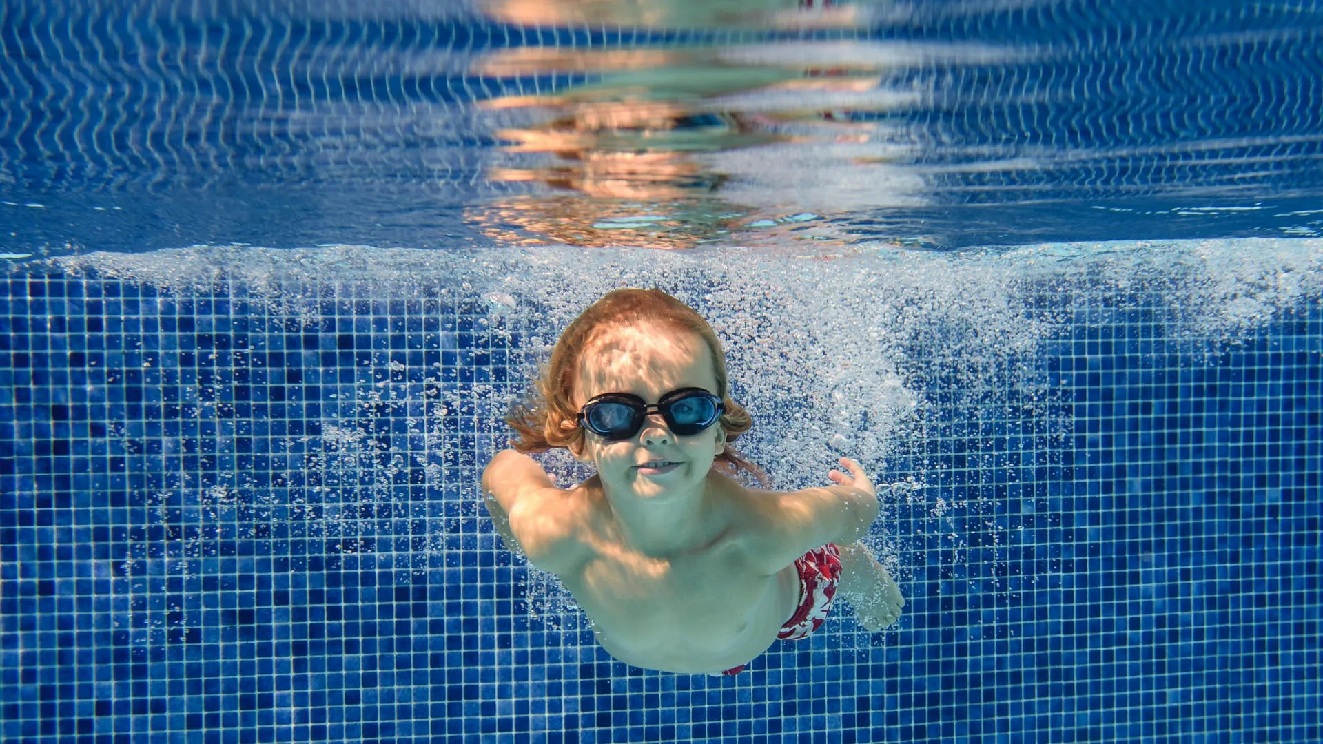 smiling-boy-swimming-underwater-in-pool-2023-11-27-05-01-40-utc